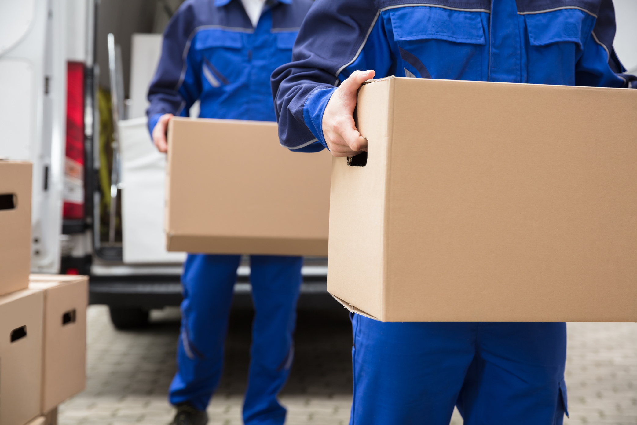 Close-up Of Two Movers Carrying Cardboard Box